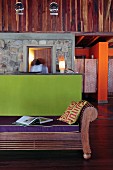 Farbkontraste im Empfangsbereich einer Öko-Lodge; Wandverkleidung und dekorative Holzbank aus afrikanischem Edelholz