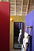 Walls painted in contrasting colours, towel rack and mirror below light roof structure of wood and bamboo