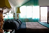 Doppelbett, flankiert von postmodernen Nachttischlampen in Schlafzimmer mit geprägter Schrägdachverkleidung