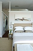 Modern artwork above bed with striped headboard in elegant bedroom; walk-in wardrobe in background