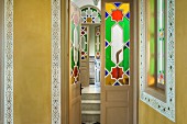 Foyer with stencilled painting on ochre yellow walls and stained glass panels in open door with view into hallway