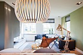 Designer Hängeleuchte aus Holzlamellen in minimalistischem Wohnraum mit Butterfly Sessel und Ledersofagarnitur