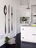 White-painted fitted kitchen with industrial-style pendant lamp and photo-realistic cutlery mural on wall