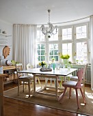 Lattice bay window in sunny kitchen-dining room with table, vintage chairs and natural fibre rug