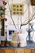 Still-life arrangement of love notes in front of vase of twigs on half-height cabinet