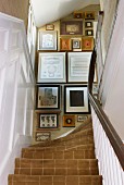 View from below of a traditional staircase with carpet and framed pictures on the wall