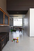 Purist living-dining room in converted school building: play area with polished concrete floor