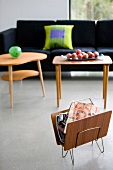 Magazine rack and 50s-style wooden side tables in front of modern sofa