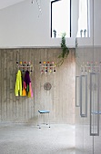 Coat racks with colourful balls on exposed concrete wall in modern foyer