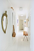Fitted cupboard and white wooden floor in narrow hallway