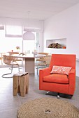 Orange armchair and wooden designer stool in front of round dining table and cantilever chairs
