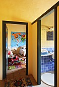Corner of hallway with yellow walls, rug and view through open door into child's bedroom and bathroom