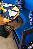 Curved bench with blue leather upholstery and table with place settings