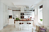 Central island with bar stools in open-plan kitchen with corner fireplace