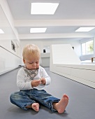 Toddler sitting on floor next to white futuristic bench in contemporary interior