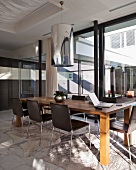 Modern wooden table and leather-covered chairs in front of glass wall in contemporary living-dining room