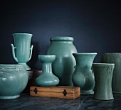 Range of different hand-thrown vases with light green glaze against black background