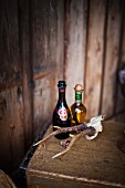 Bottle of champagne, bottle of olive oil and small set of antlers on wooden trunk