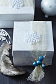 Christmas present in gift box with stylised snowflake and miniature turquoise baubles on net ribbon