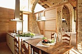 Modern kitchen island and dining area with turned, Spanish wooden chairs in spacious, restored stone house