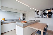 View from minimalist kitchen with breakfast bar to raised dining area