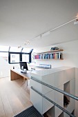 Hellse Arbeitszimmer mit Schreibtisch und Bücherbord; brüstungshohe Elementwand an der Treppe