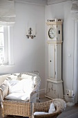 Wicker chair with white cushions and nostalgic grandfather clock in living room