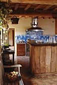 Rustic kitchen with antique blue wall tiles and simple wooden fronts combined with vintage-effect terracotta tiles