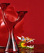 Two-armed, red glass candlestick and plastic toy against red background