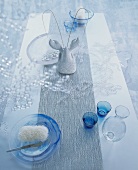 Glasses and glass dishes, some blue, on table runner