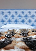 Animal skin blanket on bed with light blue satin headboard quilted with buttons