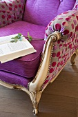Book on reading chair with gilt wooden frame and colourful, spotted modern upholstery