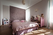 Double bed against lilac partition and soft toys on half-height shelving in modern bedroom
