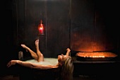 Woman bathing in wooden bathtub in candlelight