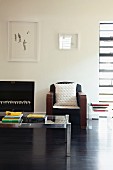 Minimalist artworks on wall above retro armchair and glass and metal coffee table