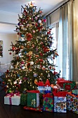 Many wrapped presents below magnificently decorated Christmas tree