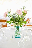 Vase of roses on set dinner table with glasses