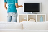 Woman pointing remote control at television
