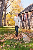 USA, New Jersey, Woman raking leaves in front of house