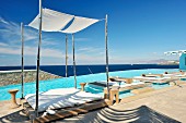 Loungers on floating wooden decks in swimming pool with view of ocean