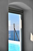View of pool and electricity pylon in front of open sea through window