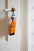 Knitted doll on vintage handle of white interior door