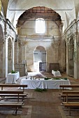 Long, festive dining tables set with white tablecloths in former monastery chapel