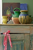 Painted ceramic vessels on vintage wooden cabinet