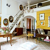 Art collection and antique furniture in London artist's apartment with ladder-style staircase leading to mezzanine