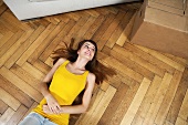 Germany, Berlin, Young woman lying on floor, smiling