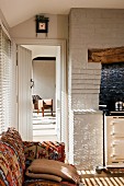 Buntes Sofa in weisser Küche mit Ziegelsteinwand und antikem Herd