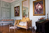 Antike Sitzbank und Kleinmöbel in herrschaftlichem Salon mit Gemälden auf bemalter Holzpaneelwand