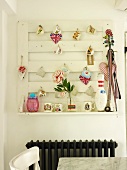 Wall-mounted peg board hung with various decorative objects above radiator in kitchen