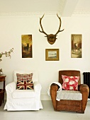 Upholstered chairs with scatter cushions, pictures with hunting motifs and antlers in living room